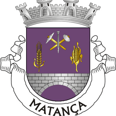 Brasão de Matança com coroa almofadada, escudo púrpura com ferramentas agrícolas e milho, e listras laterais.