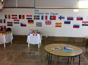 Sala de evento com bandeiras de países europeus na parede e mesas decoradas com objetos temáticos.