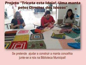 Três mulheres tricotam peças coloridas num espaço aberto, com quadrados e retângulos tricotados em várias cores sobre a mesa.
