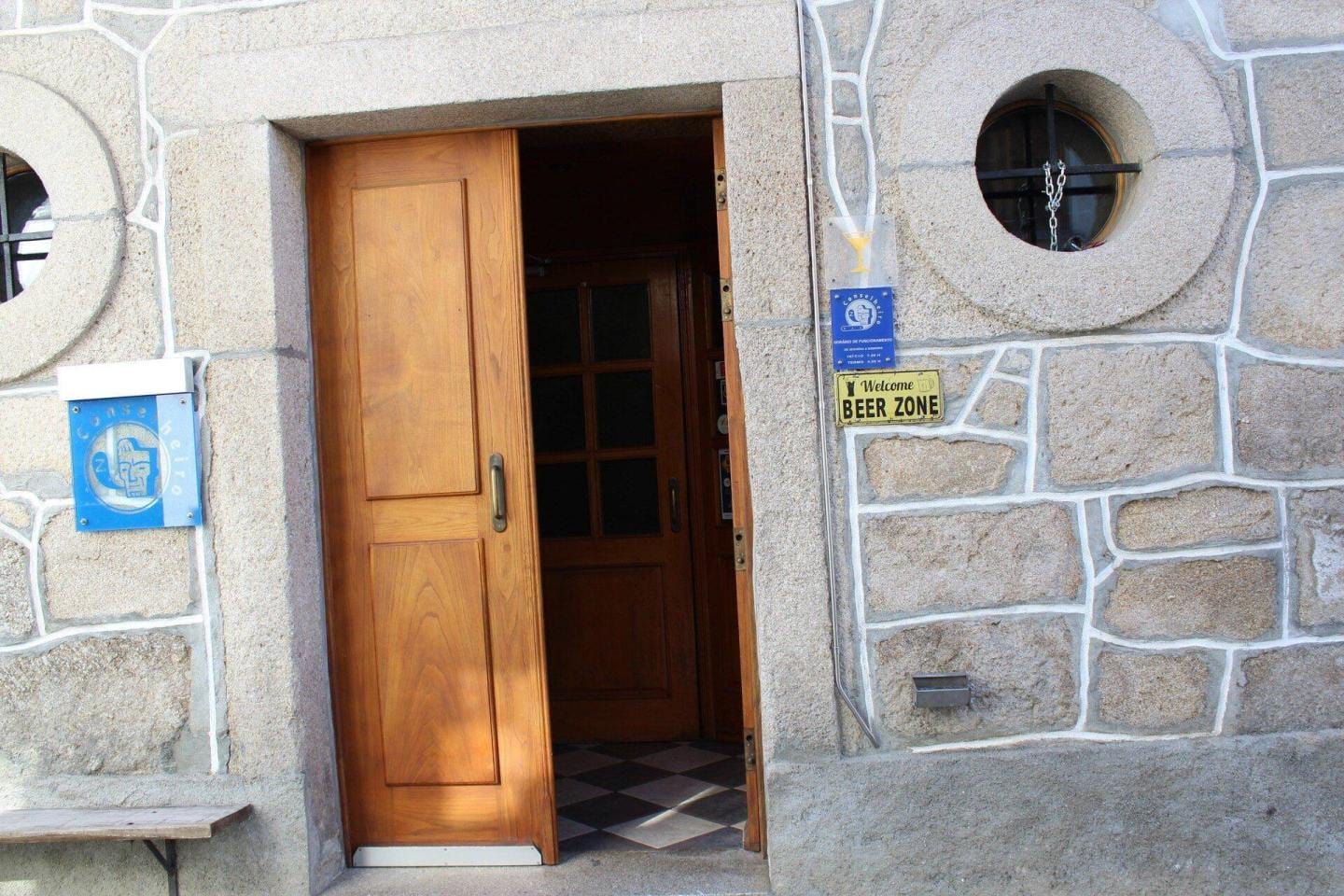 Porta de madeira aberta em fachada de pedra com sinais de