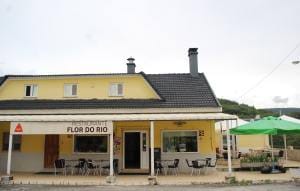Fachada amarela do Restaurante Flor do Rio com esplanada e guarda-sol verde