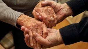 Três mãos de pessoas idosas entrelaçadas, mostrando cuidado e solidariedade.