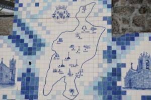 Mapa do concelho com delimitação de freguesias e ilustrações de igrejas, contornado por padrão de azulejos azuis e brancos.