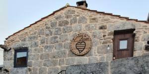 Fachada de pedra com emblema circular de coração e texto no topo