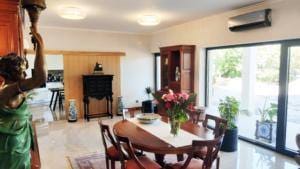 Sala com mesa de madeira, estátua grega, portas de vidro para jardim e flores frescas