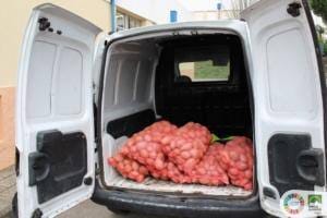 Furgão branco carregado com sacos de malha vermelha contendo batata-doce.
