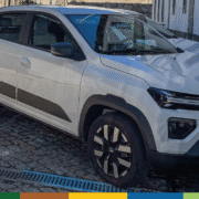 Veículo elétrico branco estacionado em pátio urbano Carro elétrico branco e preto estacionado em pátio com edifícios ao fundo