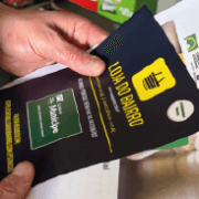 Pessoa segura cartão preto e amarelo do Munícipe em estabelecimento comercial